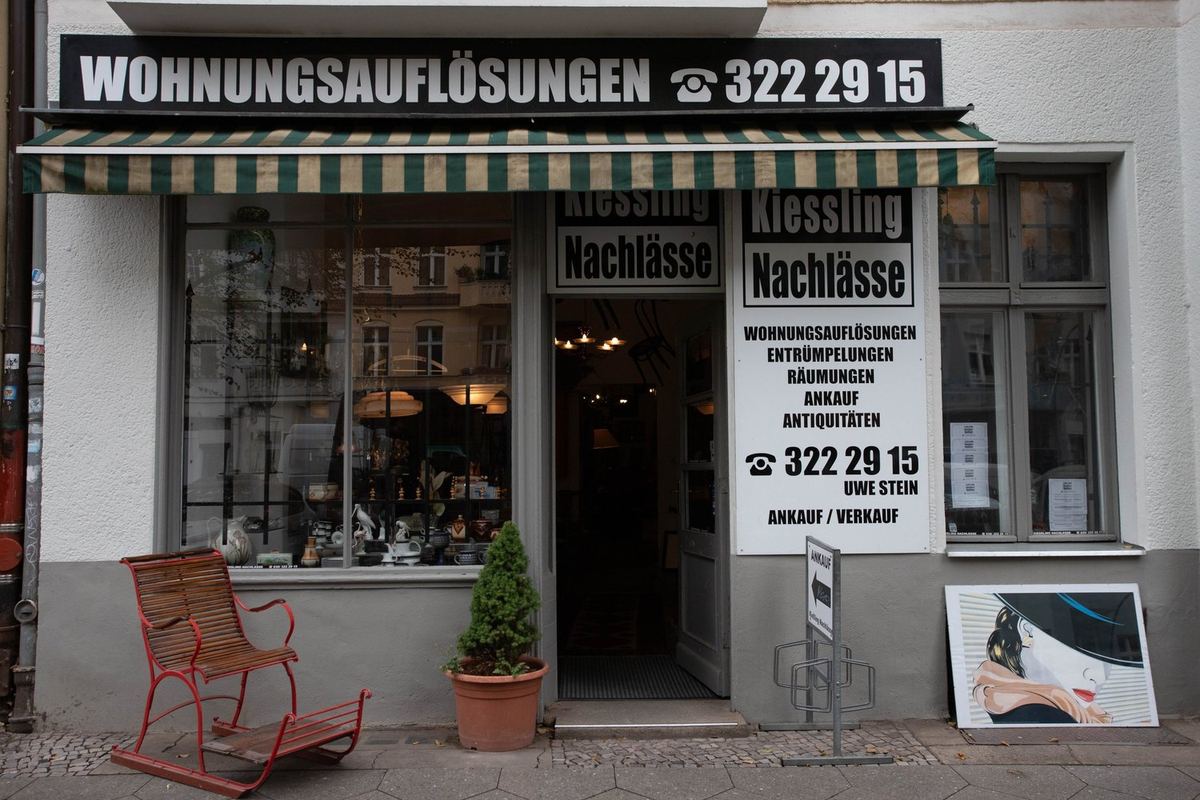 Vintage-Tischlampe mit figuraler Skulptur im Schaufenster, umgeben von Dekoration
